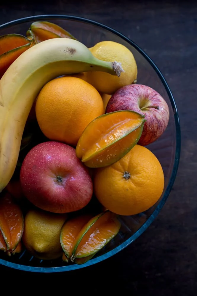 Skål med friske æbler, bananer, appelsiner og stjernefrugt