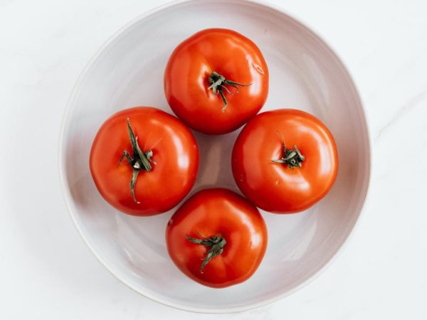 ripe tomatoes in ceramic bowl placed on marble table